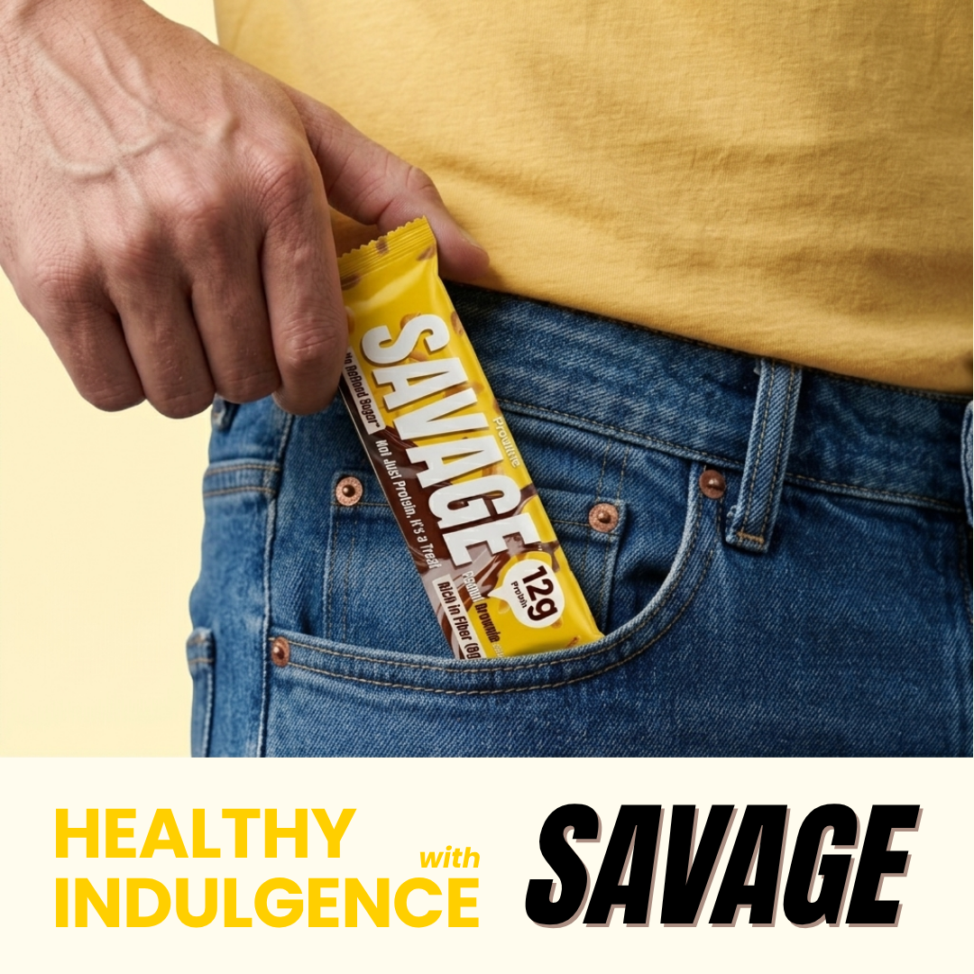 A close-up lifestyle shot of a person's hand sliding a yellow and brown 'Savage' candy bar into their blue jeans pocket, wearing a yellow t-shirt against a pale yellow background.